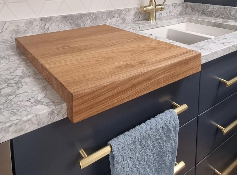The Stability Feature (Close-up): Detailed view of the 90-degree front-edge lip on a handcrafted oak carving board, demonstrating how it prevents movement during food preparation on smooth surfaces like granite or quartz.