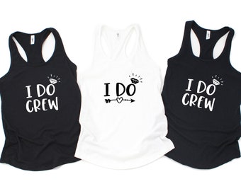 May include: Three tank tops: two black and one white. The black tank tops have the text "I DO CREW" with a diamond graphic. The white tank top has the text "I DO" with a diamond graphic, an arrow, and a heart.