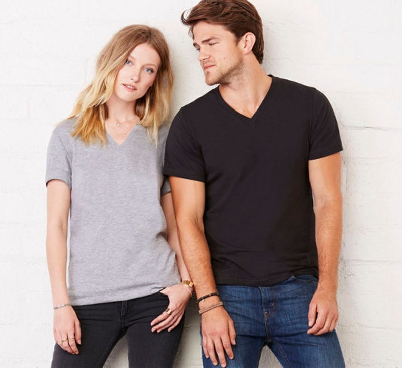 May include: Two people wearing V-neck t-shirts. The person on the left is wearing a heather grey t-shirt and the person on the right is wearing a black t-shirt.