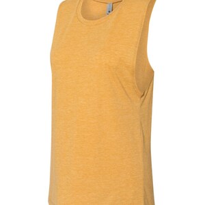 May include: A mustard yellow sleeveless shirt made of a soft, textured fabric. The shirt has a relaxed fit and a rounded neckline.