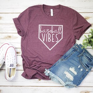 May include: A maroon t-shirt with a white baseball diamond graphic and the text "baseball vibes".