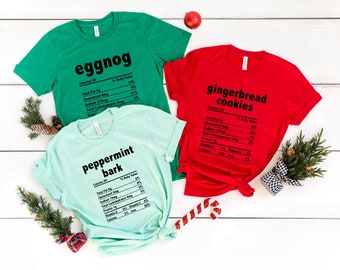 May include: Three t-shirts with a Christmas-themed food nutrition label design. The green shirt says "eggnog", the red shirt says "gingerbread cookies", and the light blue shirt says "peppermint bark".