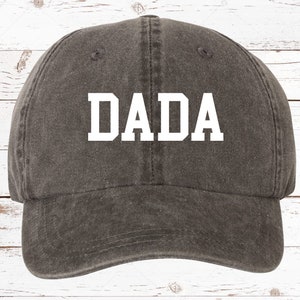 May include: A dark gray baseball cap with the word "DADA" in white block letters.