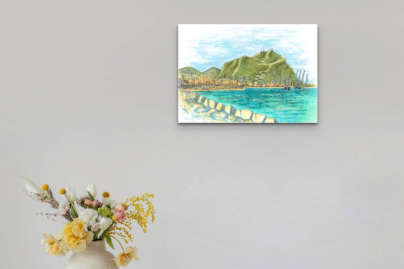 May include: A watercolor painting of a coastal town with a green hill in the background. The town is situated on the waterfront with boats docked in the harbor. The water is a bright turquoise blue.