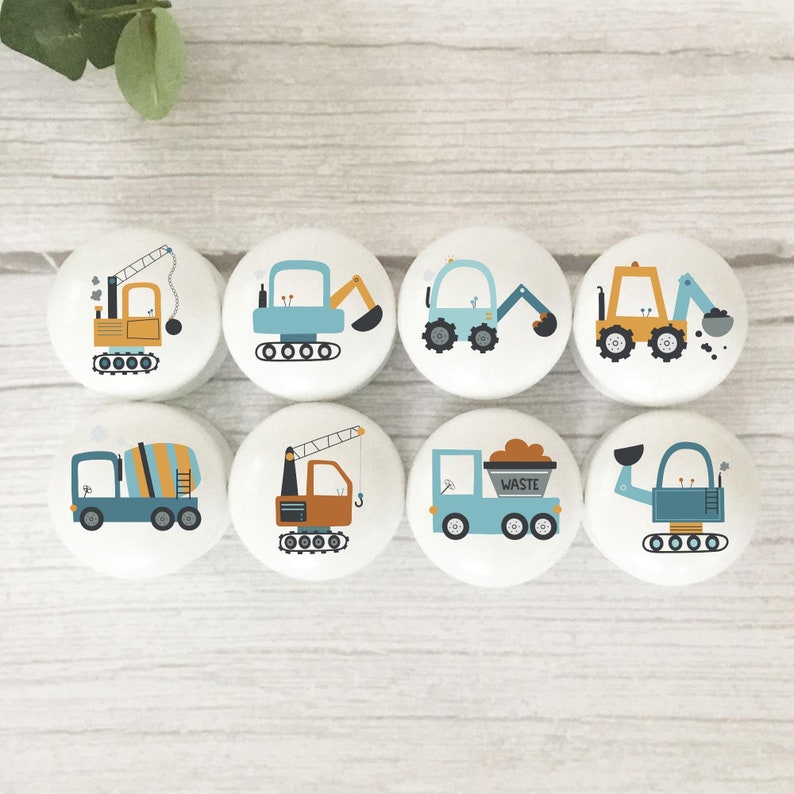 May include: Set of eight round wooden knobs with colourful illustrations of construction vehicles. The knobs feature a crane, excavator, dumper truck, cement mixer, and other construction vehicles.