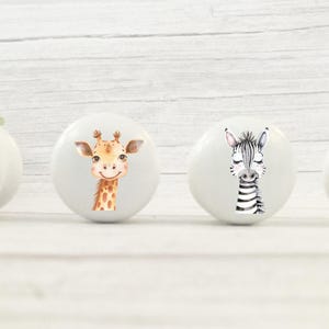 May include: Four white ceramic drawer knobs with animal illustrations. The knobs feature a cheetah, giraffe, zebra, and elephant.