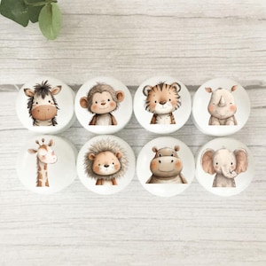 May include: Eight white cabinet knobs featuring charming watercolour illustrations of safari animals: a zebra, monkey, tiger, rhino, giraffe, lion, hippo, and elephant. Ideal for a nursery or children's room, these knobs add a playful touch.