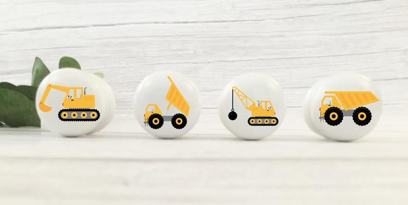 Op de afbeelding: Set van vier keramische knoppen met gele bouwvoertuigen op een witte achtergrond. De voertuigen omvatten een kiepwagen, een graafmachine, een kraan en een bulldozer.
