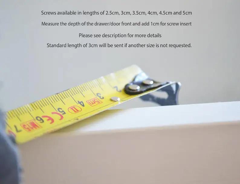 May include: A yellow measuring tape with black markings is used to measure the depth of a white drawer front. The tape reads "3 cm" and "4 cm". Screws are available in lengths of 2.5 cm, 3 cm, 3.5 cm, 4 cm, 4.5 cm, and 5 cm. Measure the depth of the drawer/door front and add 1 cm for screw insert. Please see description for more details. Standard length of 3 cm will be sent if another size is not requested.