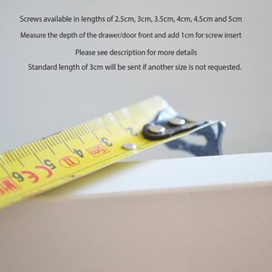 Puede incluir: Una cinta m&eacute;trica amarilla sobre una superficie blanca. El texto dice: Screws available in lengths of 2.5cm, 3cm, 3.5cm, 4cm, 4.5cm and 5cm. Measure the depth of the drawer/door front and add 1cm for screw insert. Standard length of 3cm.