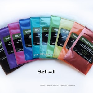 May include: Set of 10 metallic epoxy color pigments in individual pouches. The colors are black, purple, pink, blue, teal, green, yellow, orange, copper, and bronze. The pouches are labeled "ecopoxy metallic color pigment".