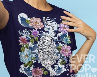 以下が含まれることがあります： 白い虎と花と波のイラストが描かれた濃い紺色のTシャツ。デザインにはピンク、紫、青の花の要素が含まれています。「EVER POP studio」の文字がシャツの右側に表示されています。