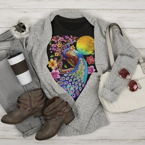 May include: Black t-shirt with a colorful peacock design on a branch with pink flowers. The peacock has blue, green, and gold feathers. There is a yellow sun behind the peacock.