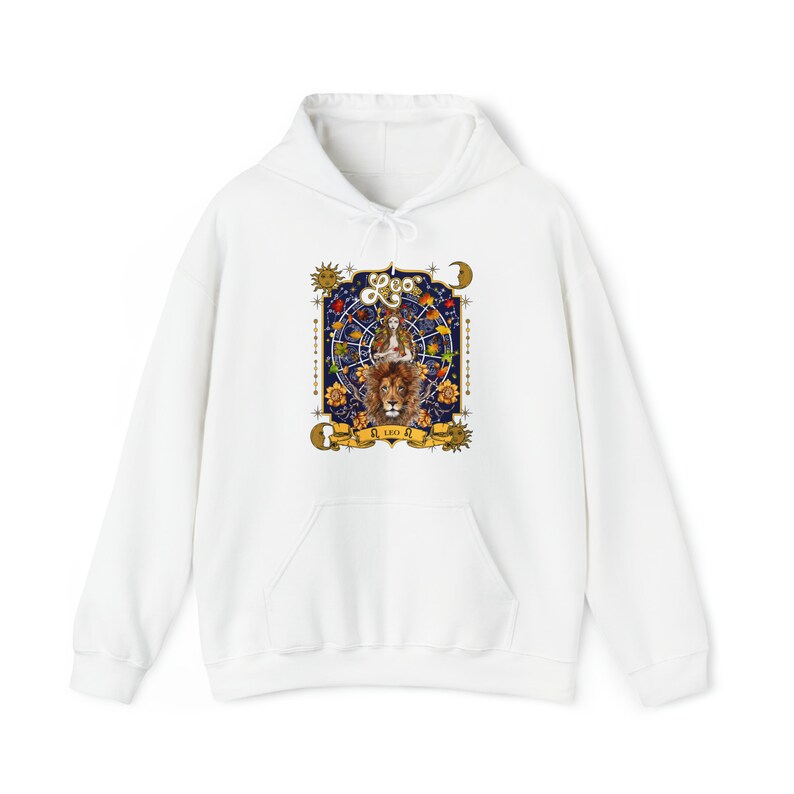 May include: White hoodie with a graphic print of a lion and a woman in a circle of stars. The graphic is surrounded by a gold frame and includes the text "Leo" and "SI LEO SI", with a sun and moon on either side.