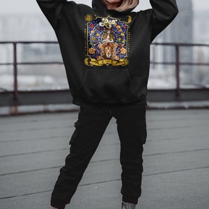 May include: Black hoodie with a graphic print of a lion and the zodiac sign Leo. The graphic features a lion with a crown, stars, and the text "Leo" in gold lettering.