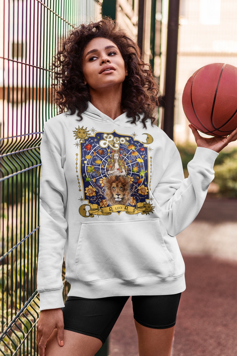 May include: White hoodie with a graphic print of a lion and a woman with a crown, surrounded by stars and flowers. The text "Leo" is printed in gold on the graphic.