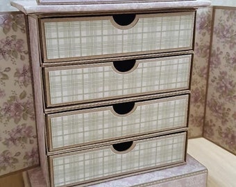 May include: A small, pink, wooden dresser with five drawers. The drawers have a plaid pattern and are accented with a decorative, scalloped base.