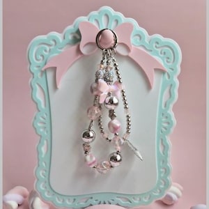 Puede incluir: Un llavero decorativo con cuentas rosas y plateadas, lazos y un dije de pluma cuelga de un marco azul claro y rosa. El texto dice: "This is a 3D Printer File. So you can only make this on a 3D Printer!!"