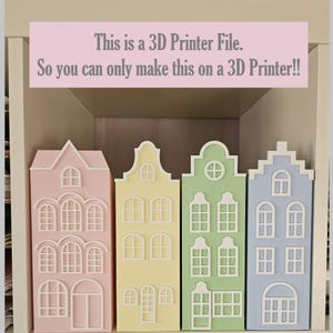 May include: Four pastel-coloured 3D-printed house models in pink, yellow, green, and blue. Each house has detailed window and door designs. The text above reads: "This is a 3D Printer File. So you can only make this on a 3D Printer!!"