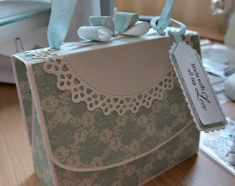 May include: A light blue and white paper gift box shaped like a handbag with a white lace trim and a tag that says "Made with all my Love".