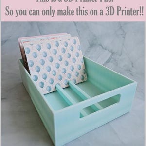 May include: A pale turquoise rectangular organiser with a handle cut-out, containing a stack of square coasters. The coasters feature a light blue balloon pattern. Text at the top reads: "This is a 3D Printer File. So you can only make this on a 3D Printer!!"