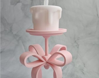 May include: A pink 3D-printed candle holder with a bow design. The candle is white and has a flame-shaped top. The text at the top says, "This is a 3D Printer File. So you can only make this on a 3D Printer!!"