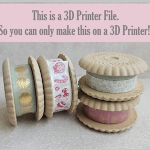 Puede incluir: Tres carretes de cinta washi en forma de galleta, impresos en 3D y de color beige. Cada carrete tiene una cinta washi estampada diferente envuelta alrededor. El texto "This is a 3D Printer File. So you can only make this on a 3D Printer!!" es visible en la parte superior de la imagen.