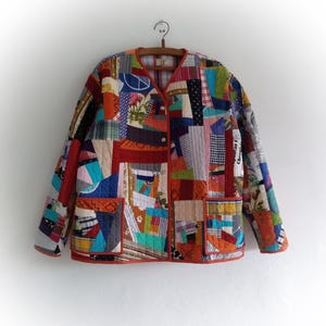 May include: A patchwork quilt jacket with a variety of colors and patterns, including red, blue, green, and yellow. The jacket has a button closure and two pockets.