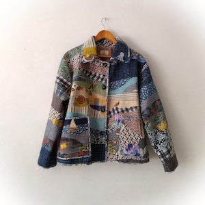 May include: A patchwork jacket in a blue, green and brown colour scheme. The jacket has a button fastening and a patch pocket on the left side.