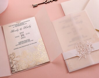 May include: A white wedding invitation with gold foil floral accents. The invitation reads "The honour of your presence is requested at the marriage of Brody & Karly, Monday, July 16, 2023, at 5 PM, Lilburn Mansion, 3899 College Ave, Historic Ellicott City, MD, Dinner and Reception to follow."