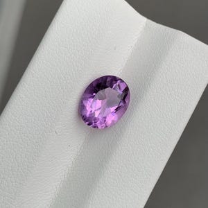 Könnte beinhalten: Ein ovaler Amethyst-Edelstein in hellvioletter Farbe.