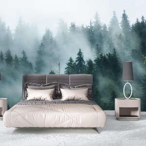 Puede incluir: Un dormitorio con un mural de pared de un bosque denso y brumoso con altos árboles de hoja perenne. La cama tiene un cabecero tapizado en gris y ropa de cama clara. Dos mesitas de noche a juego con lámparas grises flanquean la cama y un árbol en maceta.