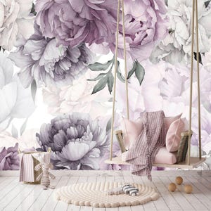 May include: A hanging wooden swing with a light pink cushion and a draped mauve throw blanket, positioned in front of a wall mural featuring large watercolor-style purple and white peony flowers, with a round beige rug on the floor.