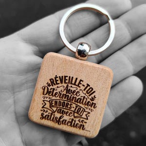 Op de afbeelding: Houten sleutelhanger met een lasergegraveerde boodschap: "Réveille-toi avec détermination Endors-toi avec satisfaction".