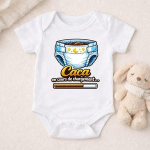 Pode incluir: Body de bebé branco com um desenho de fralda. O design da fralda inclui uma borda azul, estrelas e uma lua crescente. O texto "Caca en cours de chargement..." é impresso abaixo, juntamente com uma barra de carregamento.