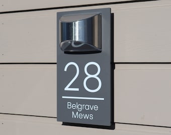 Könnte beinhalten: Ein graues Hausnummernschild mit weißem Hintergrund und der Nummer 28, den Worten Belgrave Mews und einer silbernen Leuchte.