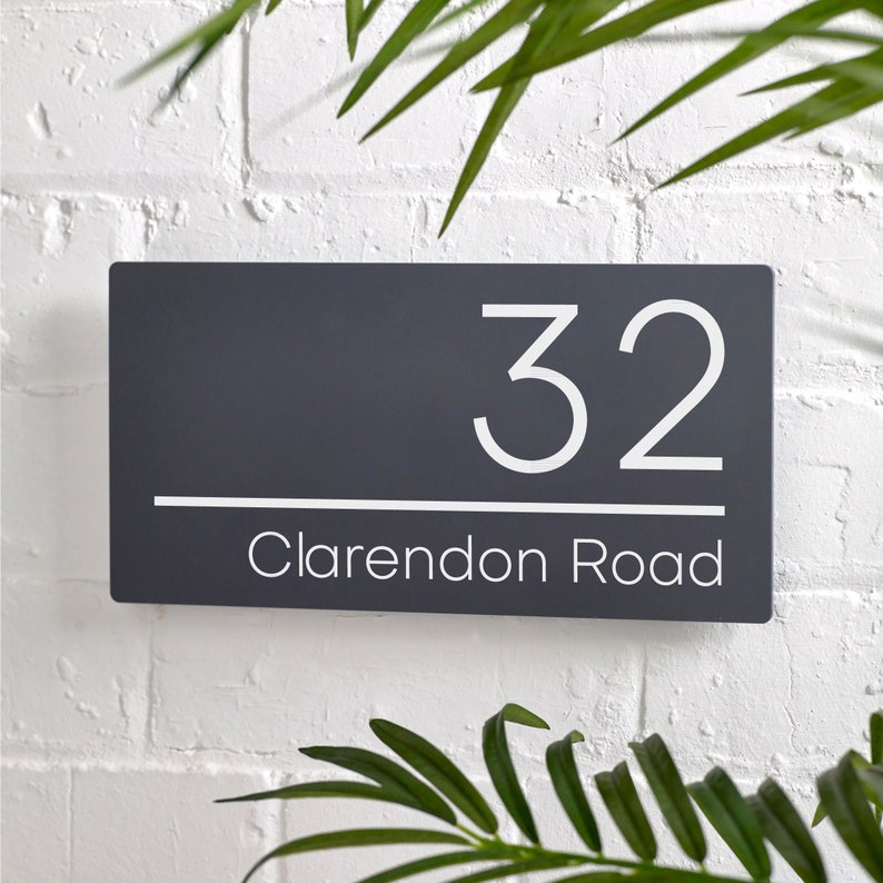 May include: A dark gray house number sign with white lettering. The number 32 is displayed above the text "Clarendon Road".