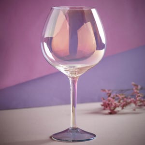 May include: A clear iridescent wine glass with a wide bowl and a long stem. The glass has a light blue tint at the base.