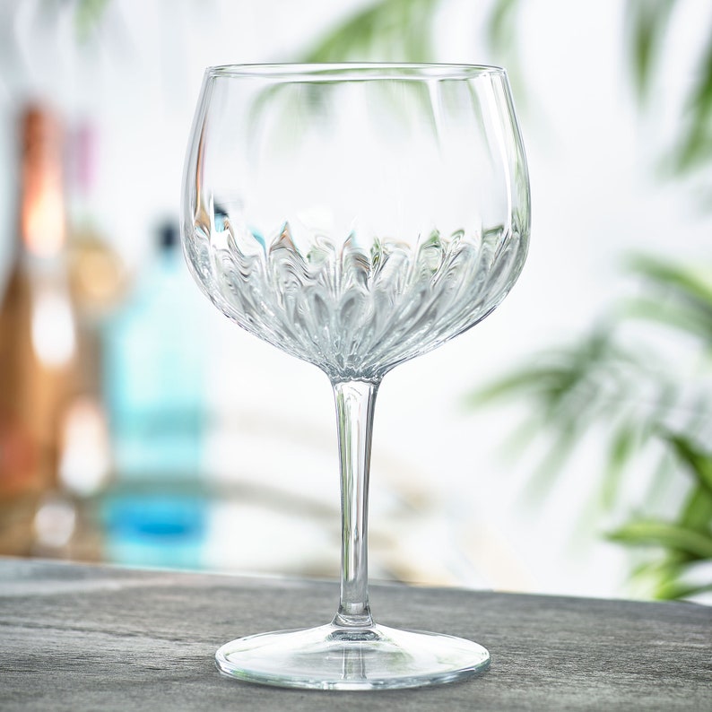May include: A clear glass gin glass with a textured, diamond-like pattern. The glass has a wide bowl and a long stem.