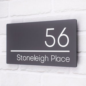 May include: A dark gray house number sign with white lettering. The number 56 is displayed above the text "Stoneleigh Place".