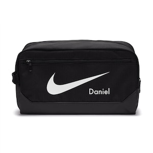 May include: Black Nike shoe bag with a white swoosh logo and the name "Daniel" printed on the front.