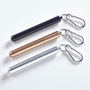 May include: Three metal straws with attached carabiners. The straws are black, gold, and silver.