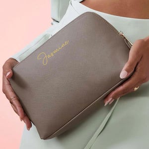 May include: A grey zipped pouch with the name "Jasmine" written in gold lettering.
