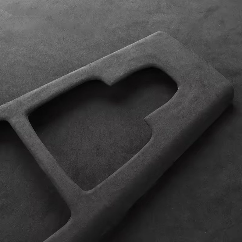 May include: A black, textured, rectangular object with a cutout in the shape of a letter "G".