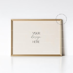 May include: A rectangular gold picture frame with a cream-colored interior. The text "YOUR design HERE" is centered in black script. The frame is set against a white background, creating a clean and elegant aesthetic.