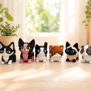 May include: A collection of eight small, stylized cat figurines arranged in a row. The cats feature various coat patterns including calico, black and white, pink and black, ginger, Siamese-style, and brown tabby, all with large, expressive eyes.
