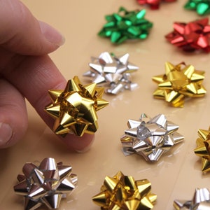 May include: Assortment of decorative gift bows in various colors, including gold, silver, red, and green. The bows are made of shiny, metallic material and have a starburst shape.