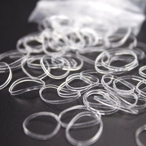 May include: A pile of clear rubber hair ties on a black surface.