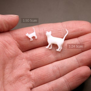 Puede incluir: Dos figuritas de gato de pl&aacute;stico blanco, una es m&aacute;s grande que la otra. El gato m&aacute;s grande est&aacute; etiquetado como "1:24 Scale" y el gato m&aacute;s peque&ntilde;o est&aacute; etiquetado como "1:50 Scale".
