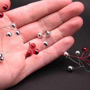 May include: A strand of red and silver bells on a wire, perfect for decorating a Christmas tree or adding a festive touch to any space.